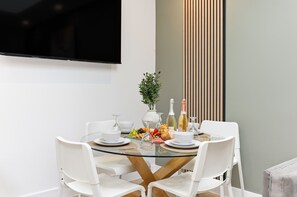 A modern dining area with a glass table, white chairs, and a variety of food and drinks. - Unique Home • Annex • Pool Table • Virgin TV • Free Parking • Self-Check-In (Northampton)