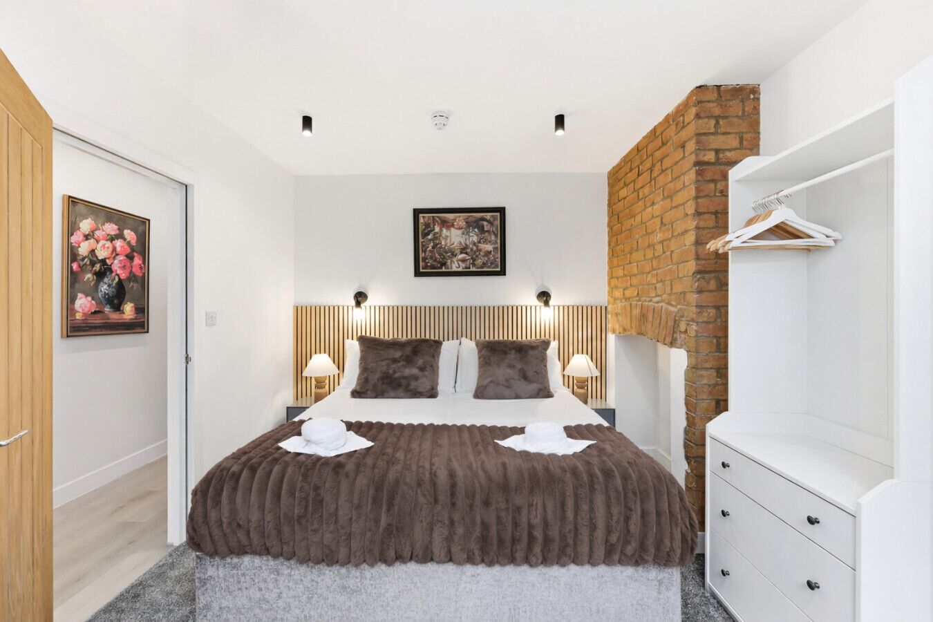Ein modernes Schlafzimmer mit einem großen Bett, einer Ziegelwand und einer weißen Kommode.