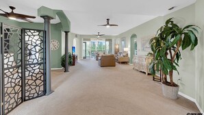 Ein geräumiges Wohnzimmer mit hoher Decke, Deckenventilatoren und einer großen Topfpflanze.