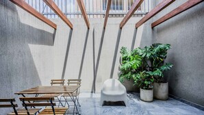 A courtyard with a wooden table and chairs, a white plastic chair, and potted plants. - NOK Spacious 3BR Apartment Near Zona T Bogota (Bogotá)