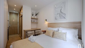 A hotel room with a large bed, a desk with chairs, a small table, and a wall-mounted artwork. - NOK Stylish 1-bedroom With Terrace on Calle 94 (Bogotá)