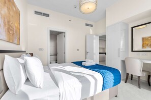 Ein modernes Hotelzimmer mit einem ordentlich bezogenen Bett, einem Schreibtisch und einem Stuhl.