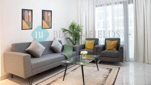 Una sala moderna con un sofá gris, una mesa de centro de vidrio y una planta en maceta.