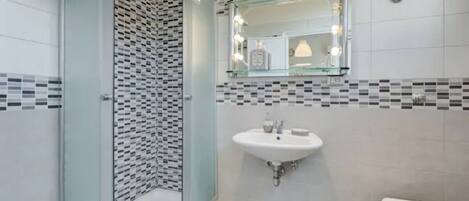 Un baño con cabina de ducha de vidrio, un lavabo blanco y un inodoro.