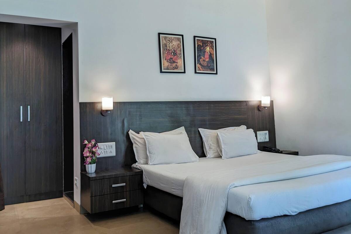 Un dormitorio moderno con una cama grande, mesitas de noche y dos lámparas fijadas a la pared.