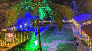 A well-lit resort area with a palm tree, pathway, and a sign for 'Ice Apparel Resort'. - ICE APPLE RESORT (Nagaon)
