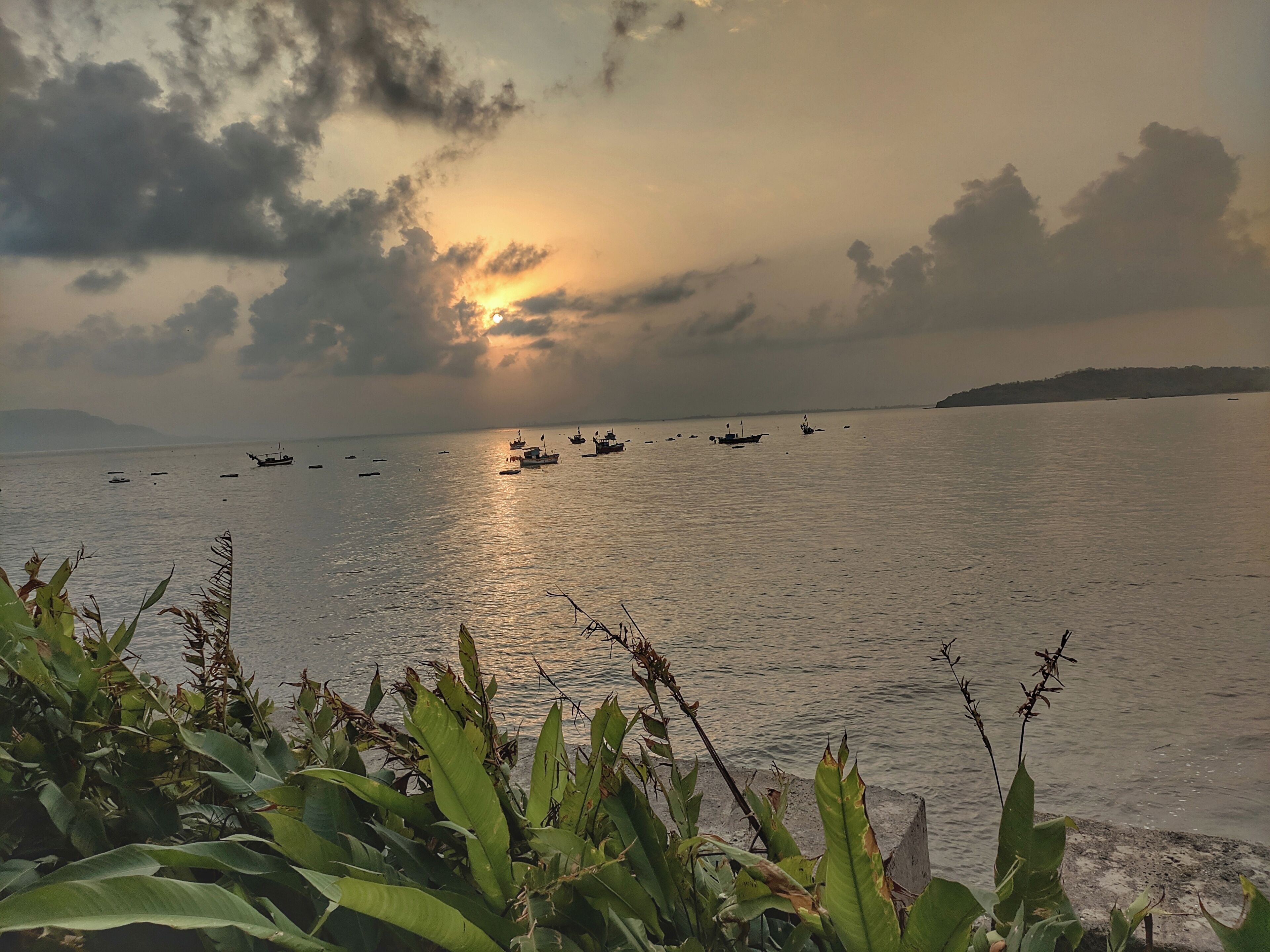 A calm sea with boats and a sunset.