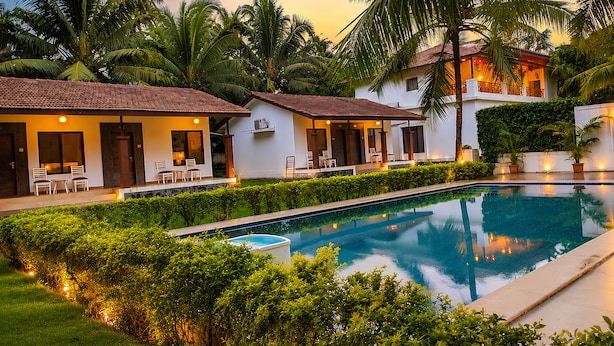 A poolside area with a clear view of the pool, a covered seating area, and lush greenery. - ICE APPLE RESORT (Nagaon)