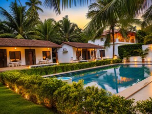 Un área junto a la piscina con vista despejada, una zona de estar techada y abundante vegetación.
