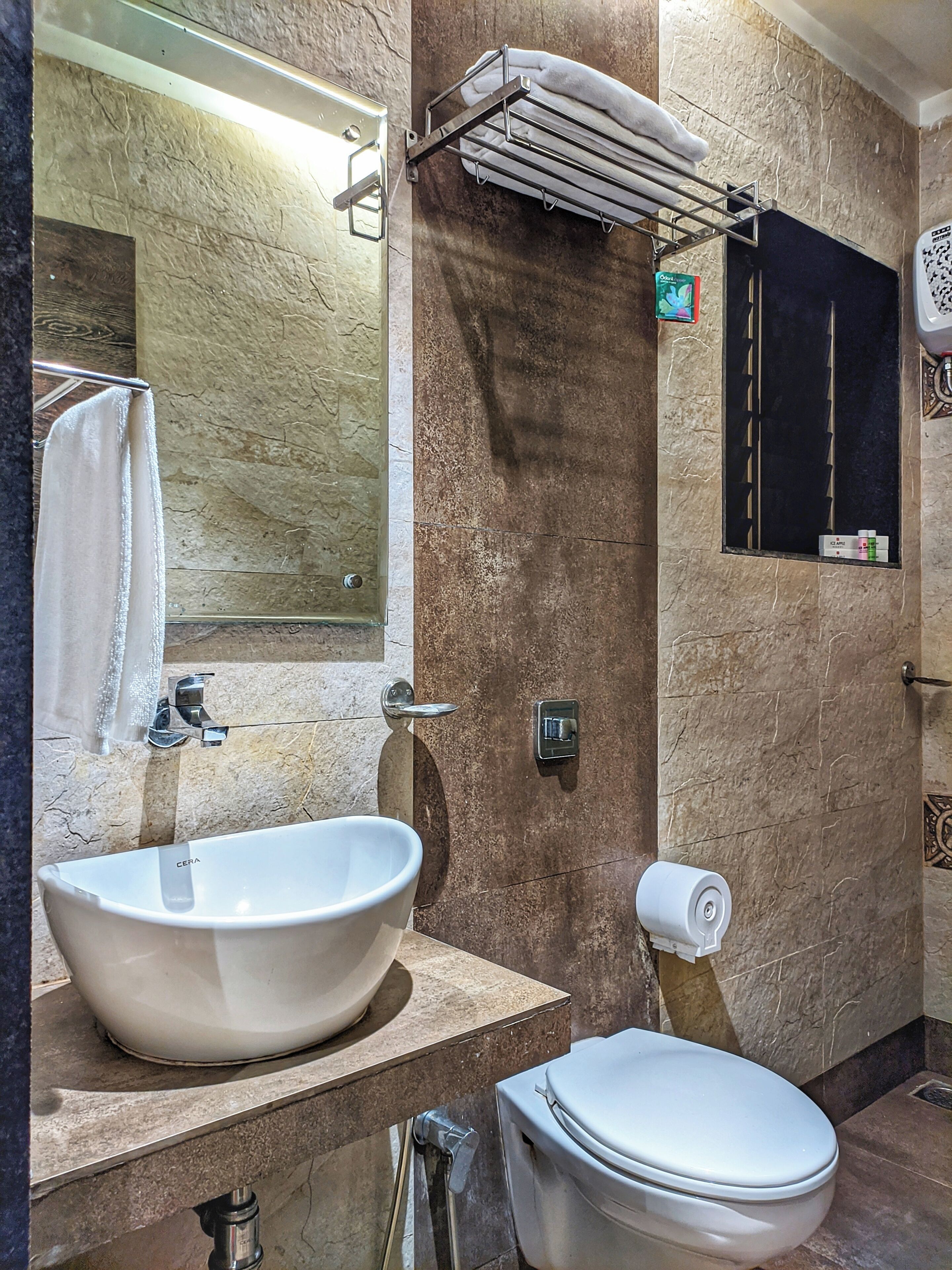 Ein Badezimmer mit einem großen, weißen Waschbecken, einer Toilette, einem Handtuchhalter und einem daran hängenden Handtuch.