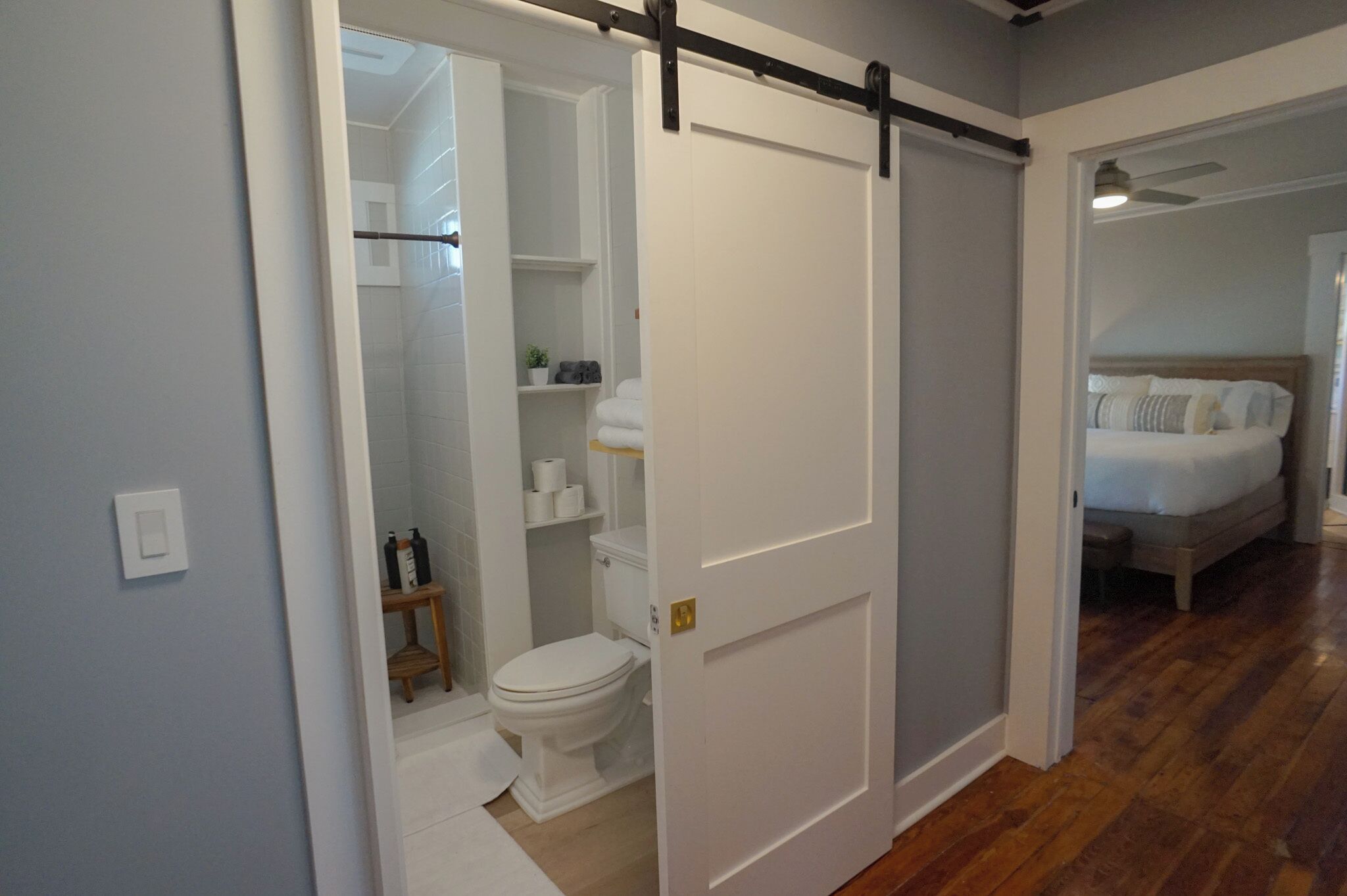 Een badkamer met toilet, toilettasjes op planken en een douchegedeelte.