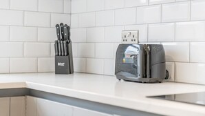 Une cuisine avec des carreaux blancs, un grille-pain et un bloc à couteaux.