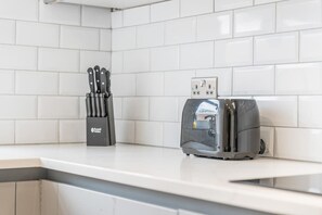 A kitchen with white tiles, a toaster, and a knife block. - Dunchurch Home|Free Parking|Contractors & Families (Dunchurch)