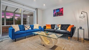 Un salon moderne avec un canapé bleu, un canapé noir et une table basse en verre.
