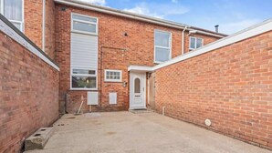 A brick building with a garage door, a small door, and a concrete driveway.