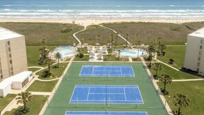 Ein Tennisplatz mit Pool und Blick auf den Strand.