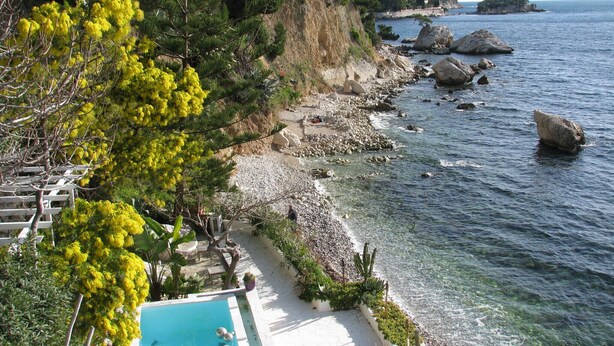 Un hotel sul lungomare con piscina, costa rocciosa e mare cristallino.