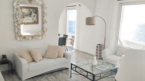 Un soggiorno moderno con un divano bianco, un tavolino in vetro e un grande specchio con cornice decorativa.