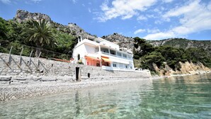 Una proprietà costiera con un edificio bianco, acque limpide e scogliere rocciose.