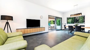 A modern living room with a flat-screen TV, a floor lamp, and a dining area with a table and chairs. - Villa Sirene by Villas Guide (Rovinj)