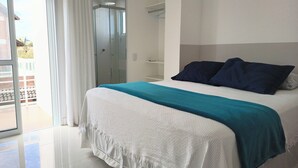 Un dormitori amb llit, un bany amb dutxa i un balcó.