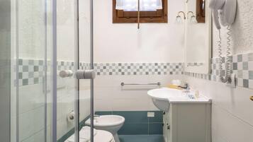 Une salle de bain équipée d’une douche à parois de verre, de toilettes, d’un bidet, d’un lavabo et d’un miroir avec un téléphone.