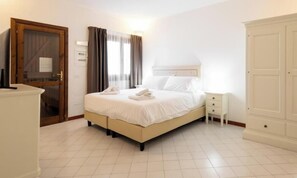 A bedroom with a bed, bedside table, and wardrobe. - Hotiday Punta Sardegna (Costa Serena)