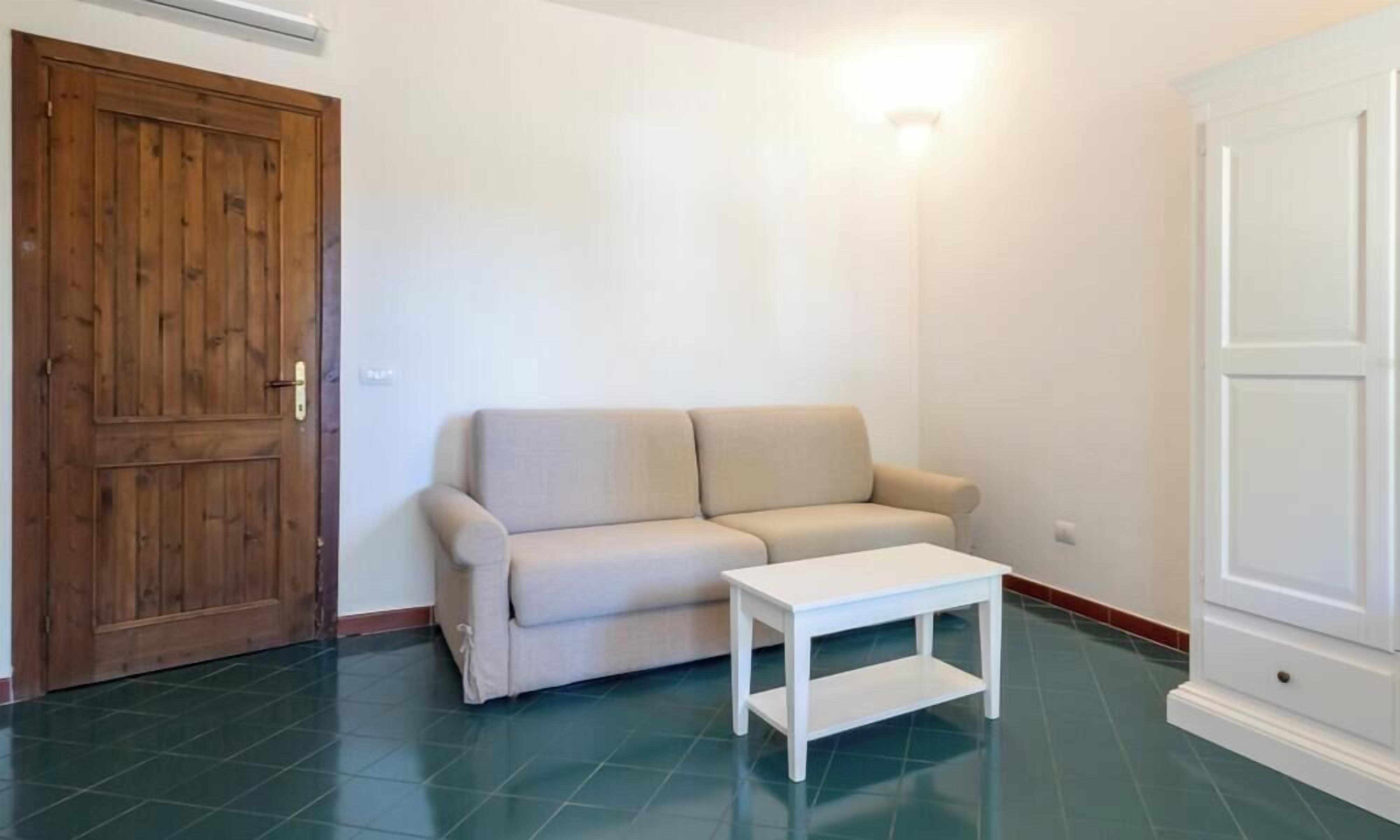 A room with a beige sofa, a white coffee table, and a wooden door.