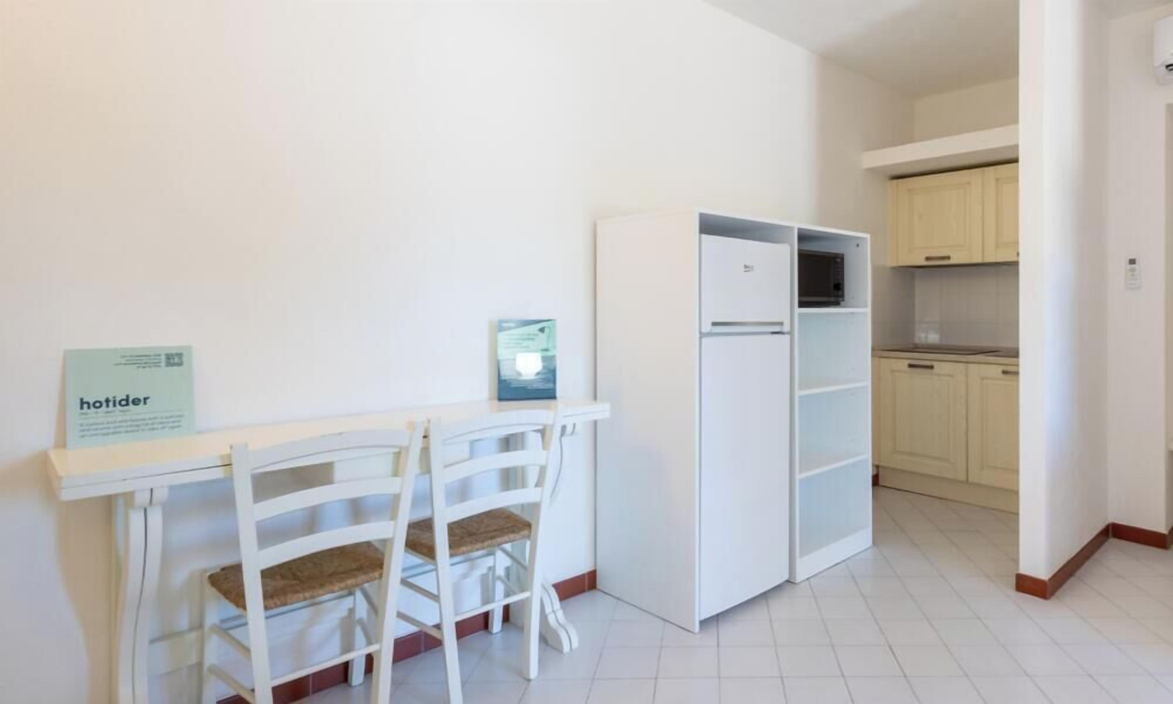 Une petite cuisine équipée d’un four à micro-ondes, d’un réfrigérateur et d’un coin repas avec deux chaises et une table.