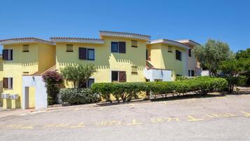 A yellow building with multiple windows and a parking lot in front.