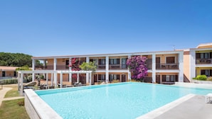 A hotel with a swimming pool, multiple balconies, and a clear sky. - Hotiday Punta Sardegna (Costa Serena)