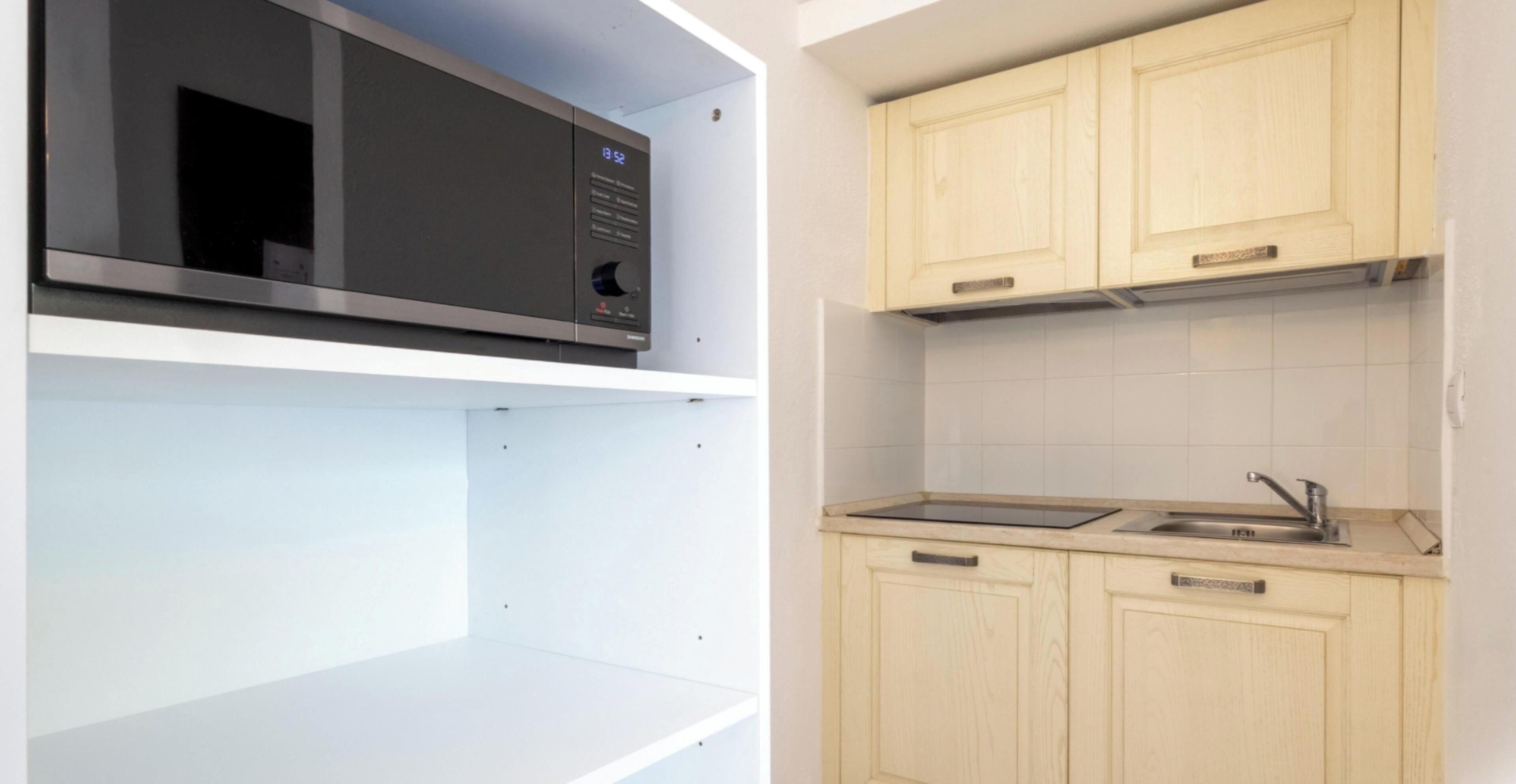 A kitchen with a microwave, sink, and wooden cabinets.