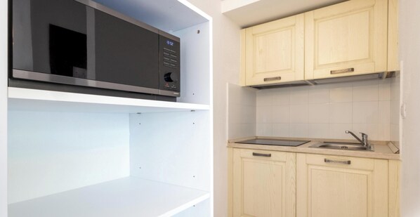 A kitchen with a microwave, sink, and wooden cabinets. - Hotiday Punta Sardegna (Costa Serena)