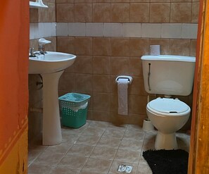 A bathroom with a sink, toilet, and a trash bin. - Casa Vacaional (Rodeo)