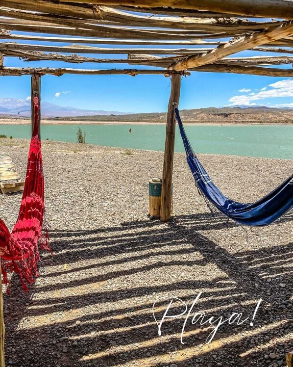 A hammock under a wooden structure by a lake with a clear sky. - Casa Vacaional (Rodeo)