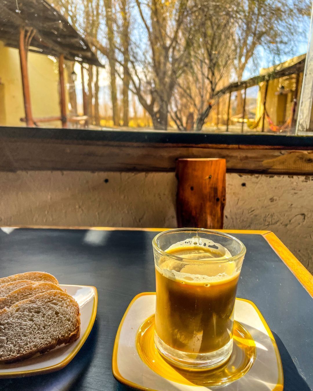 A table with a glass of iced coffee and two slices of bread on a tray.