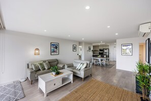 Ein modernes Wohnzimmer mit Sofa, Couchtisch und einem Essbereich im Hintergrund.