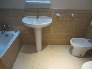 A bathroom with a pedestal sink, a bathtub, and a small toilet. - Sirocco 2º Playa de la Concha (Oropesa del Mar)