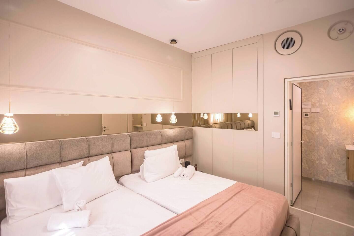 A hotel room with a large bed, a mirror, a wardrobe, and a bathroom with a shower.