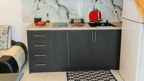 A compact kitchen with marble backsplash, dark cabinets, and a small countertop. - Filippos Traditional Villa - Pool Garden Gem (Finiq)