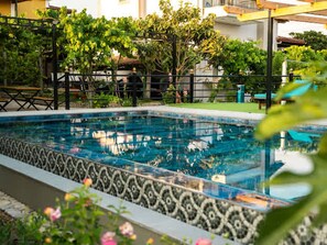 A swimming pool with a decorative border, surrounded by greenery and a fence. - Filippos Traditional Villa - Pool Garden Gem (Finiq)