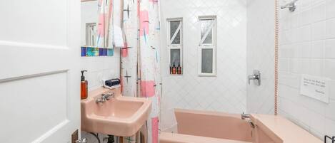 Ein Badezimmer mit Waschbecken, Toilette und Badewanne. Es gibt ein Fenster und eine Dusche.