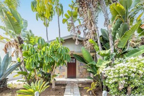 Un jardin tropical avec un sentier de pierres menant à une porte en bois portant l’inscription « 525 ».