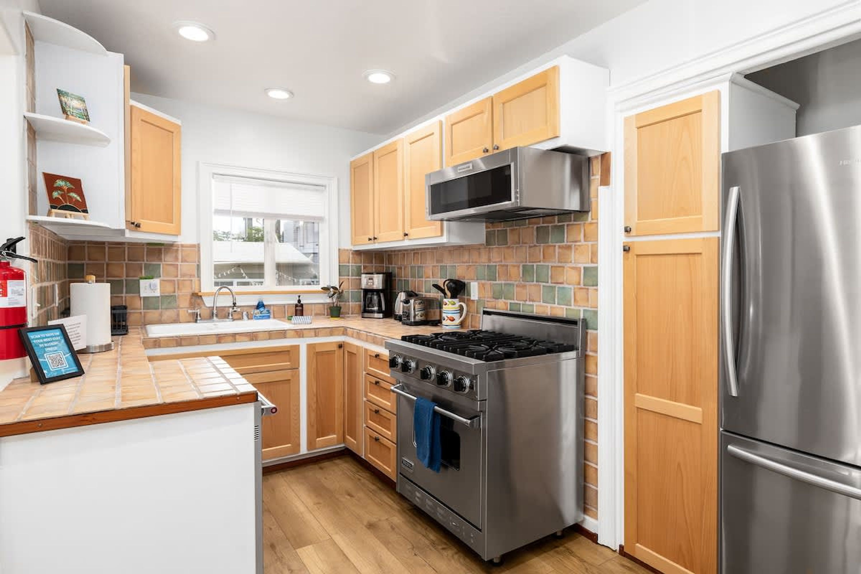 A modern kitchen with wooden cabinets, stainless steel appliances, and a tiled backsplash.