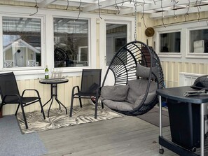 A cozy outdoor seating area with a hanging chair, a table, and chairs. - 4 Star Holiday Home in Bergkvara (Bergkvara)