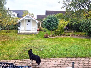 Un jardín con un gazebo blanco, un perro y un camino de ladrillo.