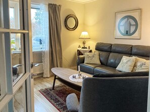 A living room with a sofa, a coffee table, a lamp, and a mirror on the wall. - 4 Star Holiday Home in Bergkvara (Bergkvara)