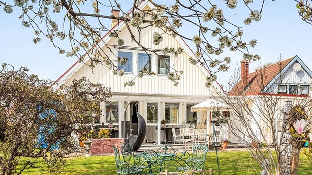 A two-story house with a large front yard, a dining area with outdoor furniture, and a garden with various plants and flowers. - 4 Star Holiday Home in Bergkvara (Bergkvara)