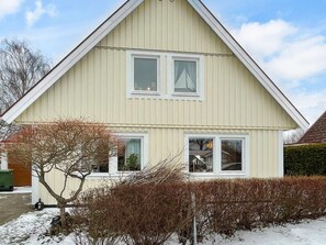 A two-story house with a gabled roof, white siding, and a small front yard with a tree and shrubbery. - 4 Star Holiday Home in Bergkvara (Bergkvara)