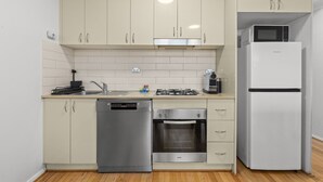 Una cocina compacta con armarios color beige, lavavajillas, horno, microondas y refrigerador.
